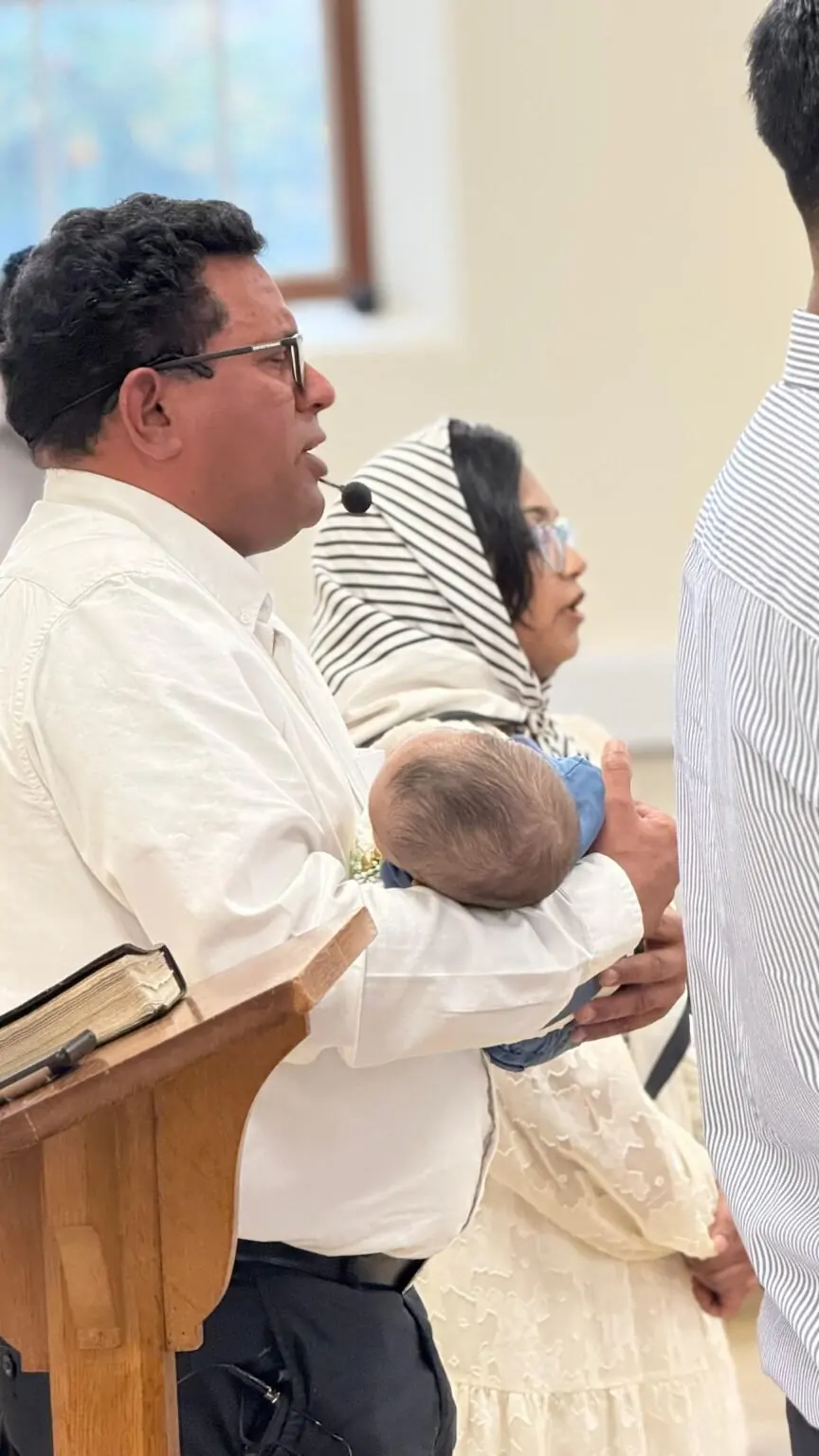 A pastor praying over a baby at a child dedication